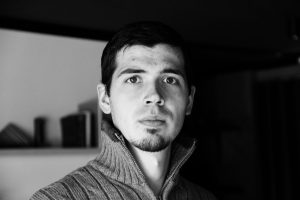 Black and white portrait of a man with a thoughtful expression indoors.