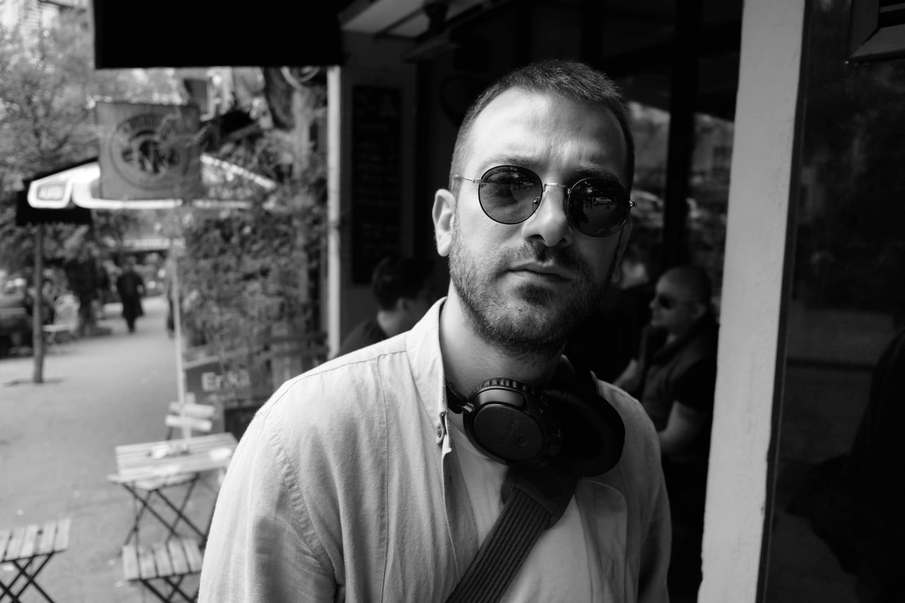 Portrait of a stylish man with headphones on a lively city street.